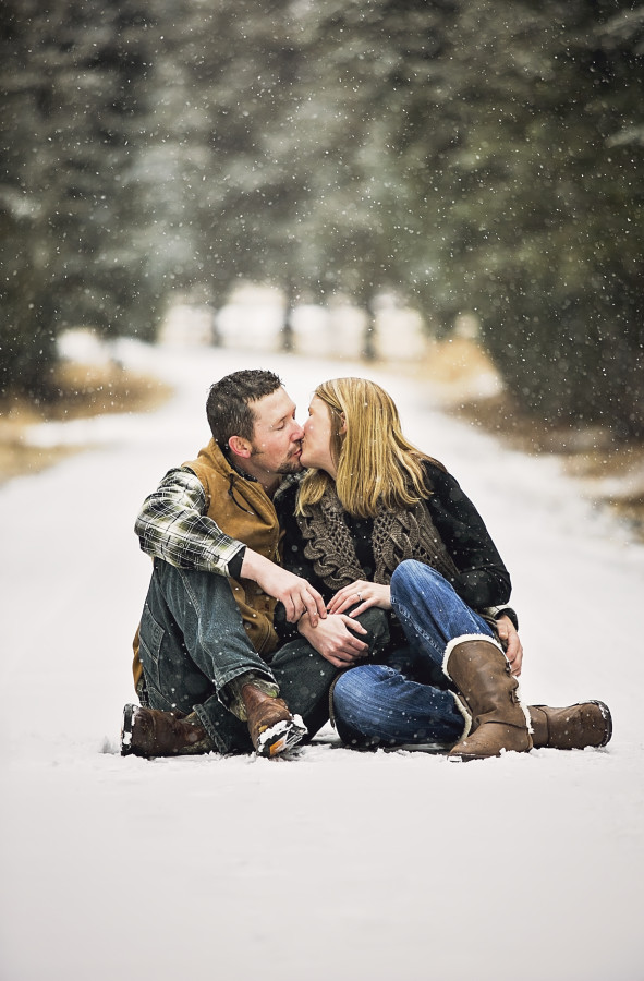 engagement-couple-sitting-kissing-in-snow